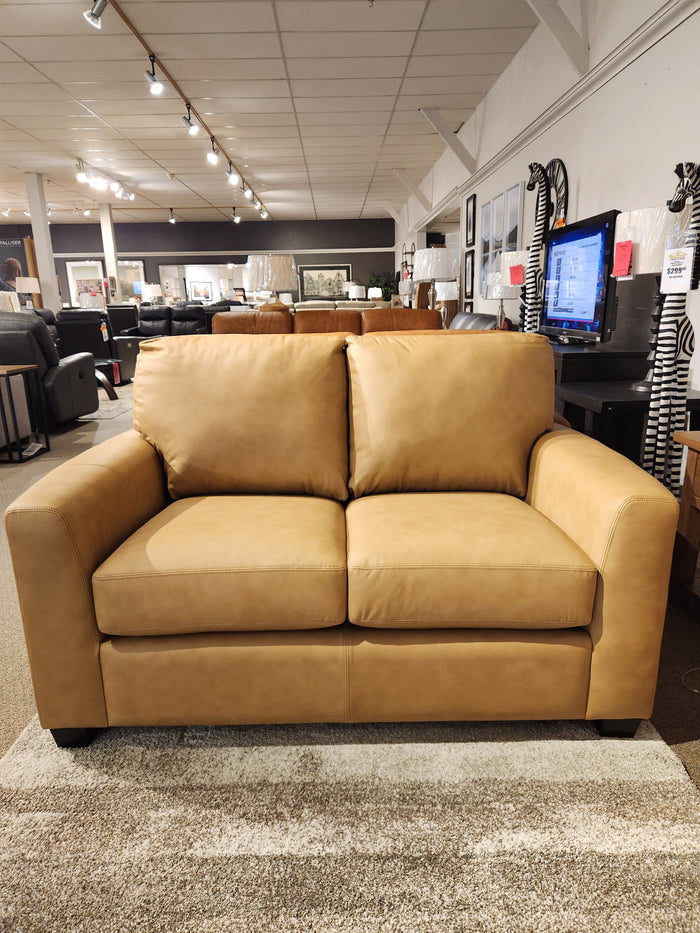 The Decor-rest 3968 Loveseat features tan leather, Canadian upholstery, deep seats, and is displayed in a modern showroom.