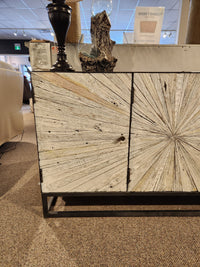 The Jofran 1929 Astral Plains 3 Door Cabinet features starburst textured doors, styled in a showroom.