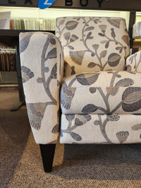 Close-up of La-z-boy 431 Scarlett High-Leg Recliner, a beige chair with gray floral pattern on display in store.