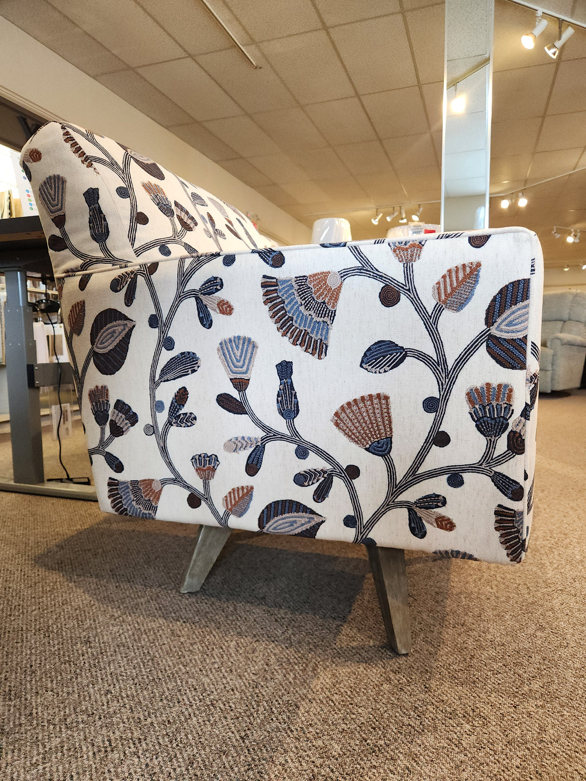 Side view of La-Z-Boy 421-210 Bellevue High Leg Swivel Chair with floral upholstery and angled wooden legs.