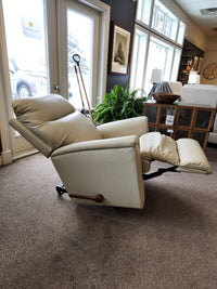 The La-Z-Boy 820 Norton Wall-A-Way Recliner in beige is displayed in a showroom with windows, plants, and chairs.