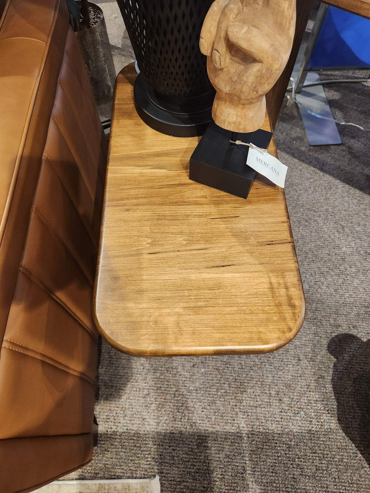 A Handstone Lotus Chairside Table holds a sculpture and black lamp next to a leather chair.