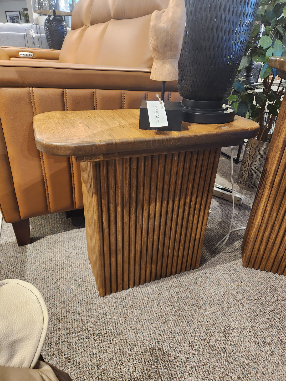 The Handstone Lotus Chairside Table features a classical slat base beside a tan sofa and decorative accents.