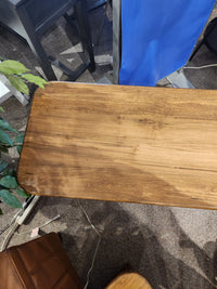 The Handstone Lotus Sofa Table sits on a carpeted floor, surrounded by furniture, a plant, and visible cords.