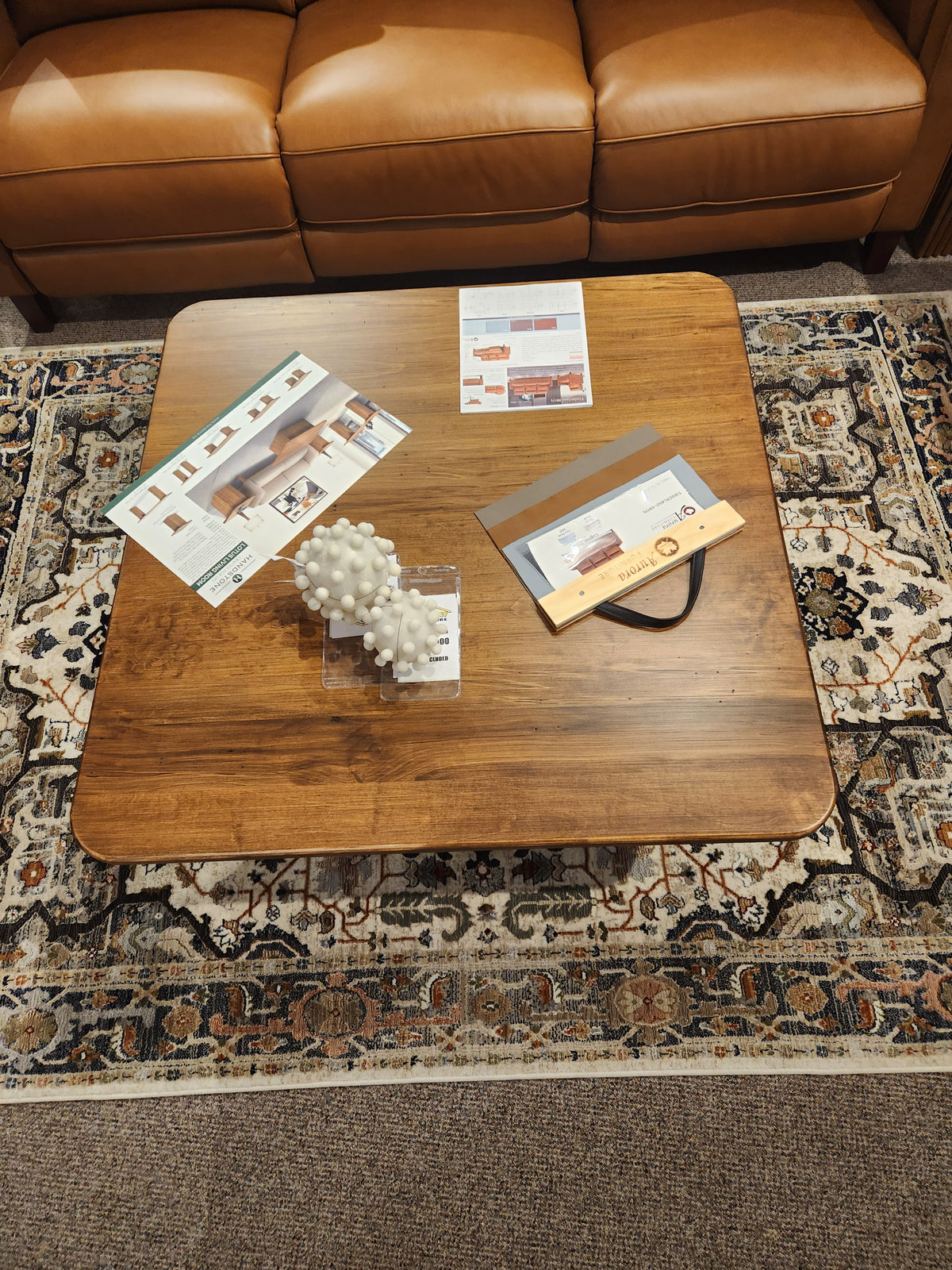 The Handstone Lotus Coffee Table sits on a patterned rug, highlighting elegant style and tasteful decor.