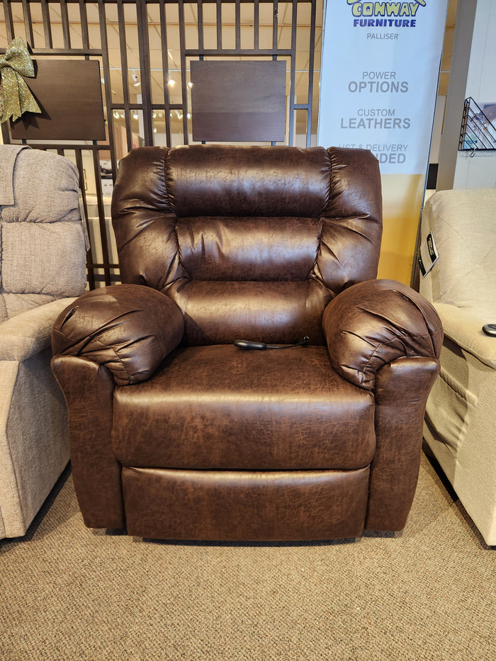 The Best 1B52 Troubadour Lift Chair is shown in a showroom, featuring brown leather and a remote on the seat.