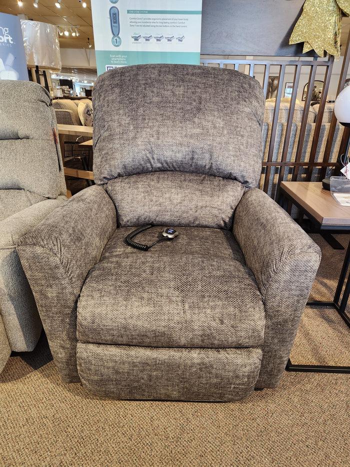 The La-z-boy 793 Jean Bronze Lift Chair in gray is shown with a remote control in a furniture store showroom.