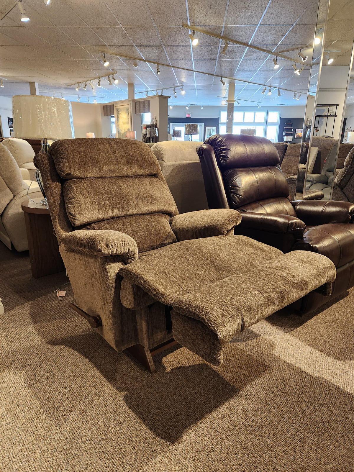 The La-z-boy 519 Astor Rocker Recliner, brown upholstered with footrest extended, is displayed in a showroom.