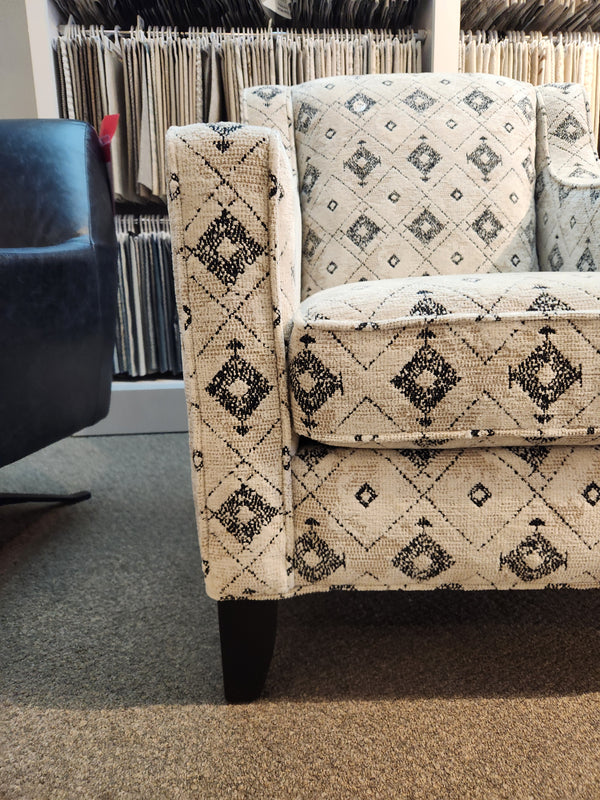 A Superstyle 828 Jasmine Chair with black diamond designs is on a carpeted floor beside a dark blue chair.