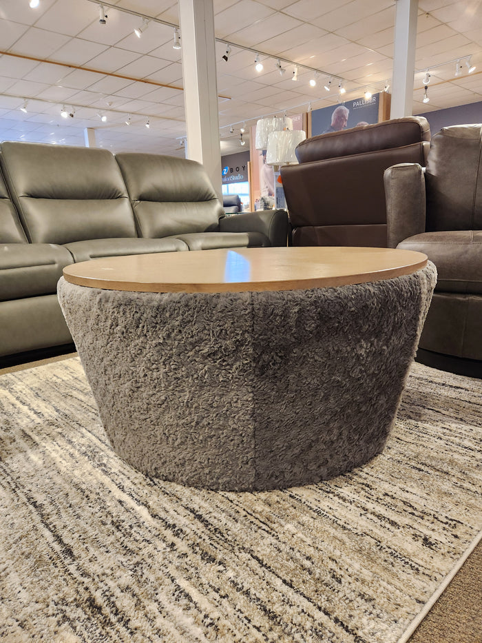 The Decor-rest 6415 Lift Top Storage Ottoman/Coffee Table features a wooden top and textured gray base, styled on a rug.