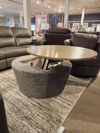 The Decor-rest 6415 Lift Top Storage Ottoman/Coffee Table is shown between leather sofas in the showroom.