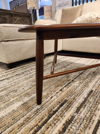 The Palliser 7110 Kacia Tri Coffee Table with tapered legs sits on a patterned carpet beside a beige upholstered sofa.