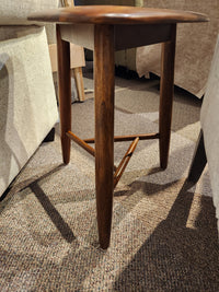 The Palliser 7110 Kacia Tri end Table, with three legs and triangular support, sits on a carpeted floor between chairs.