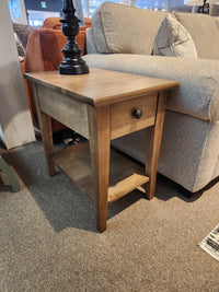 Durham 905 16"x24" End Table in Champagne with drawer and shelf, next to beige sofa topped with a lamp.