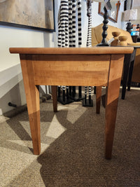 The Durham 905 20" x 24" End Table in Aged Wheat with tapered legs is displayed on a carpeted showroom floor.
