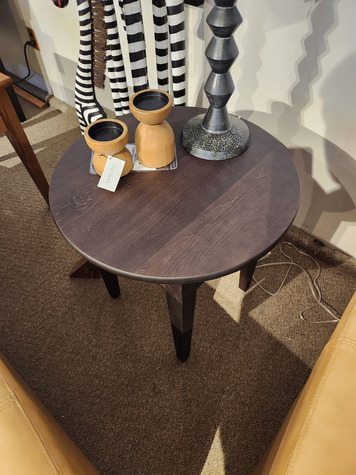 Durham 905-24" round table in Java, styled with two wooden vases, lamp, and striped decor on tan carpet.