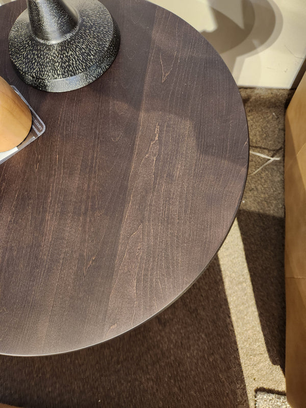 Durham 905- 24" Round Table in Java; sunlight casts shadows across its compact surface on a carpeted floor.