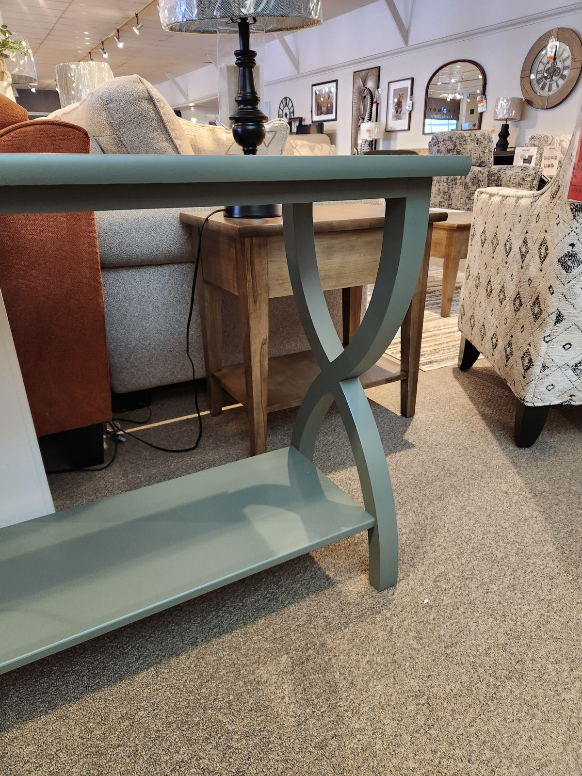 The Durham 900- Transitional Sofa Table with curved legs sits among contemporary furniture in a stylish living space.