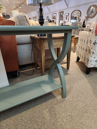 The Durham 900- Transitional Sofa Table with curved legs sits among contemporary furniture in a stylish living space.
