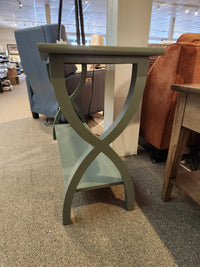 The Durham 900- Transitional Sofa Table is a small green table with crossed legs, perfect for modern living spaces.