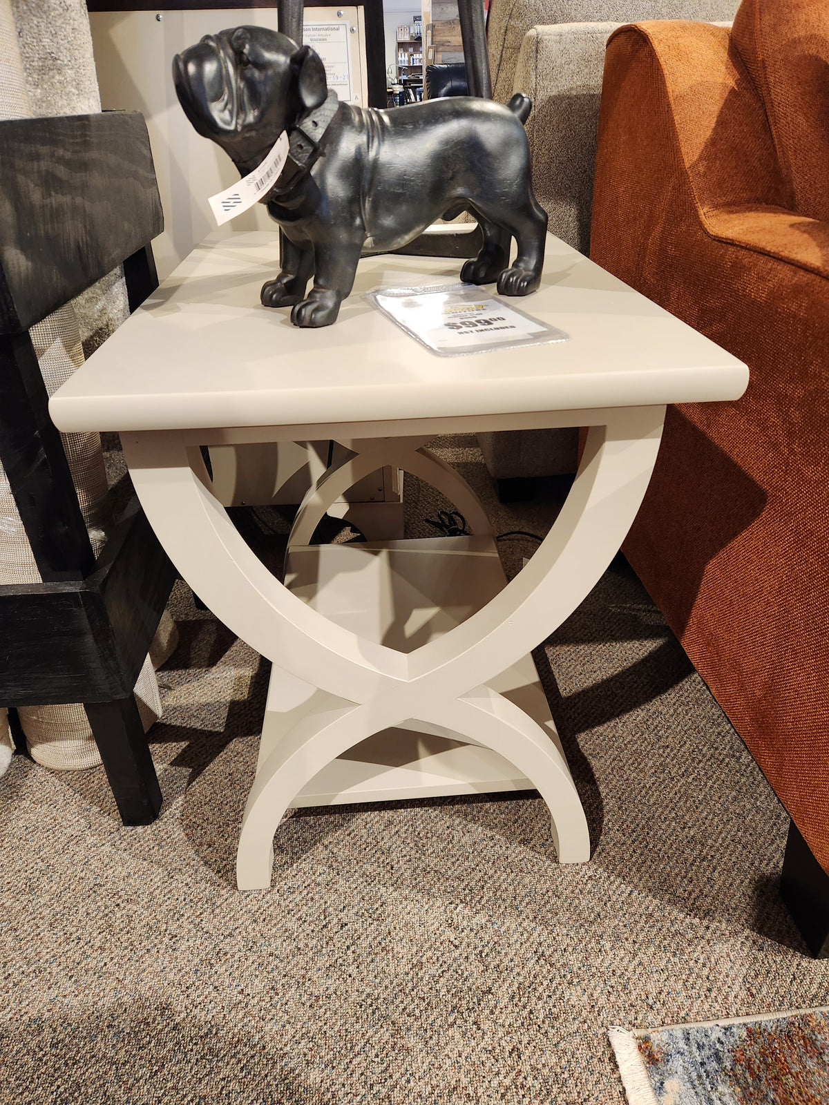 The Durham 900-534 Transitional End Table features X-legs, a lower shelf, and fits perfectly beside an orange sofa.