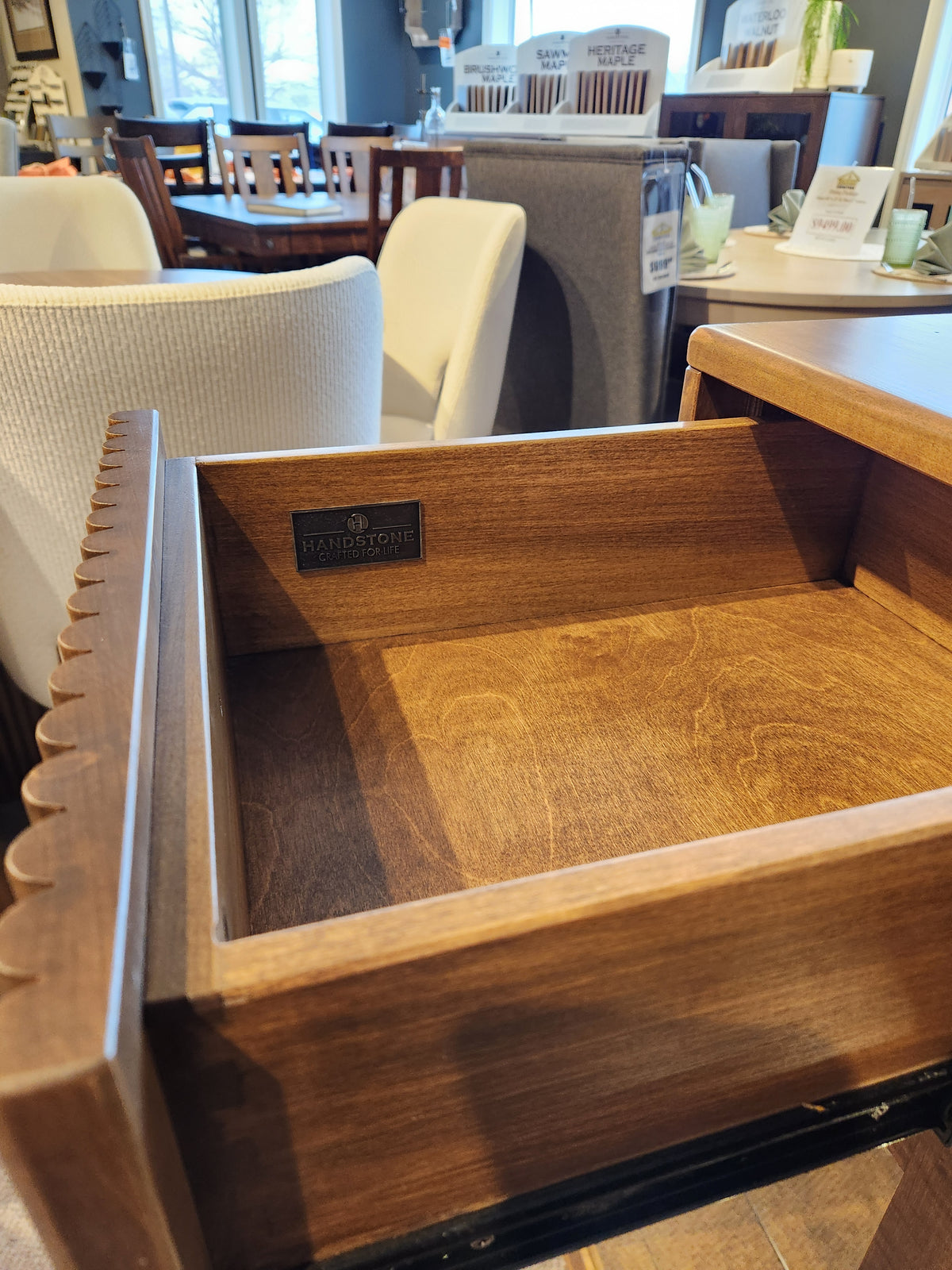 Open wooden drawer of the Handstone Lotus Dining Sideboard with Pot Lights, seen in a stylish furniture showroom.