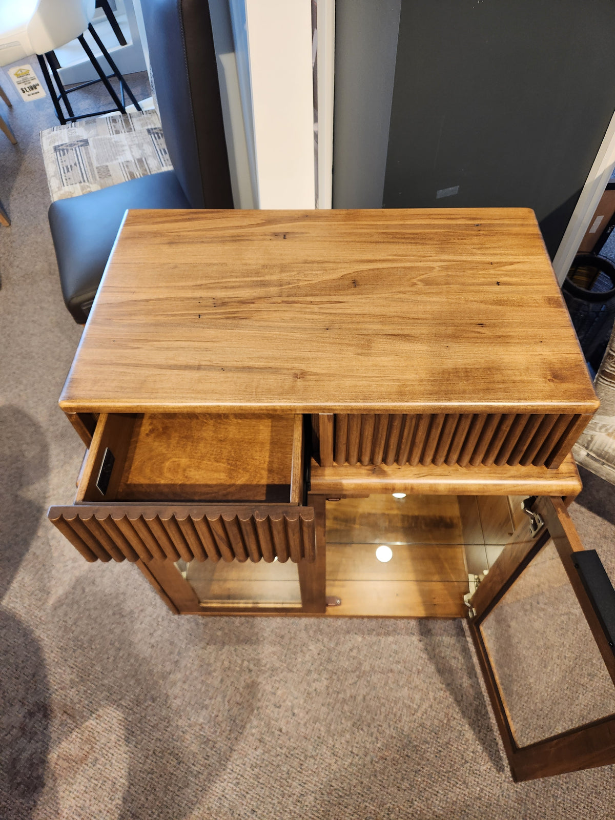 Handstone Lotus Dining Sideboard with pot lights, glass door, shelf, and open drawer shown from above in showroom.