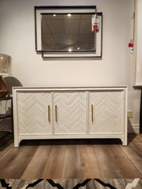Jofran Gramercy 3 Door Accent Cabinet features gold handles and chevron inlay, shown with a wall mirror above.