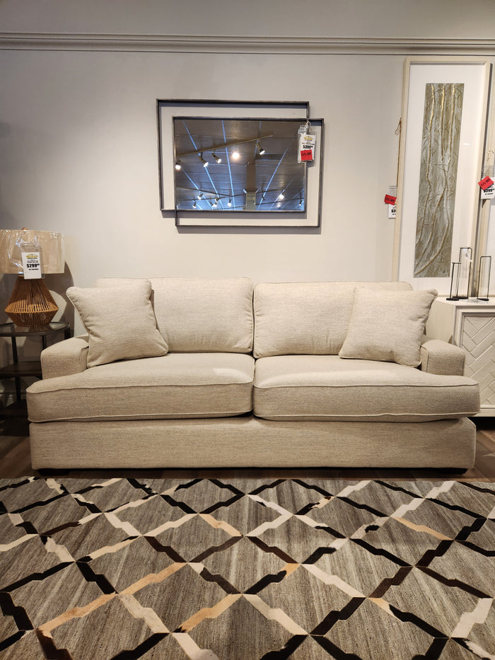 The La-z-boy 663 Paxton Sofa with ComfortCore® cushions sits in a showroom before a geometric rug and wall mirror.