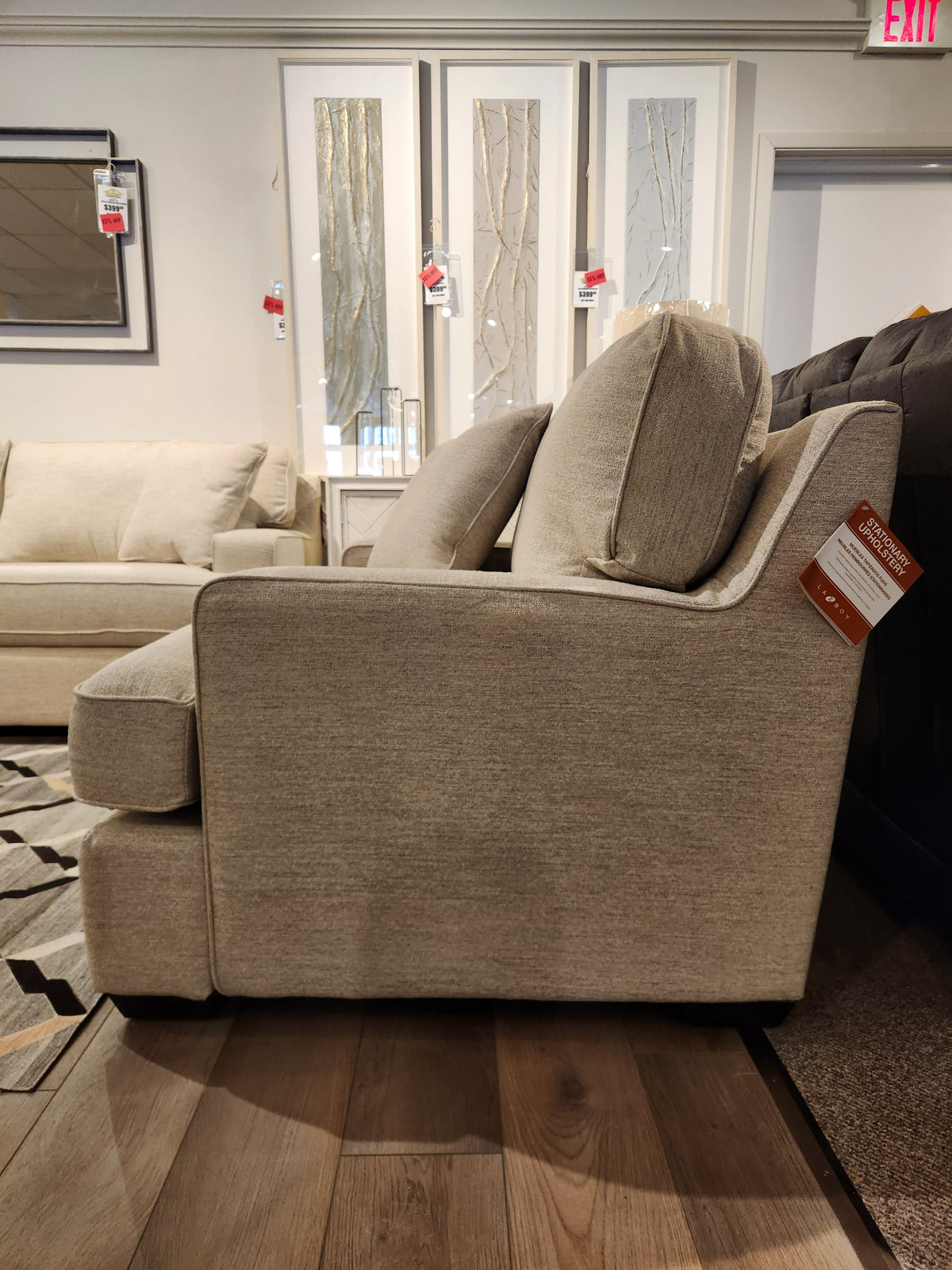 Side view of La-z-boy 663 Paxton Chair & 1/2 in beige fabric with ComfortCore cushion, price tags visible on wood floor.