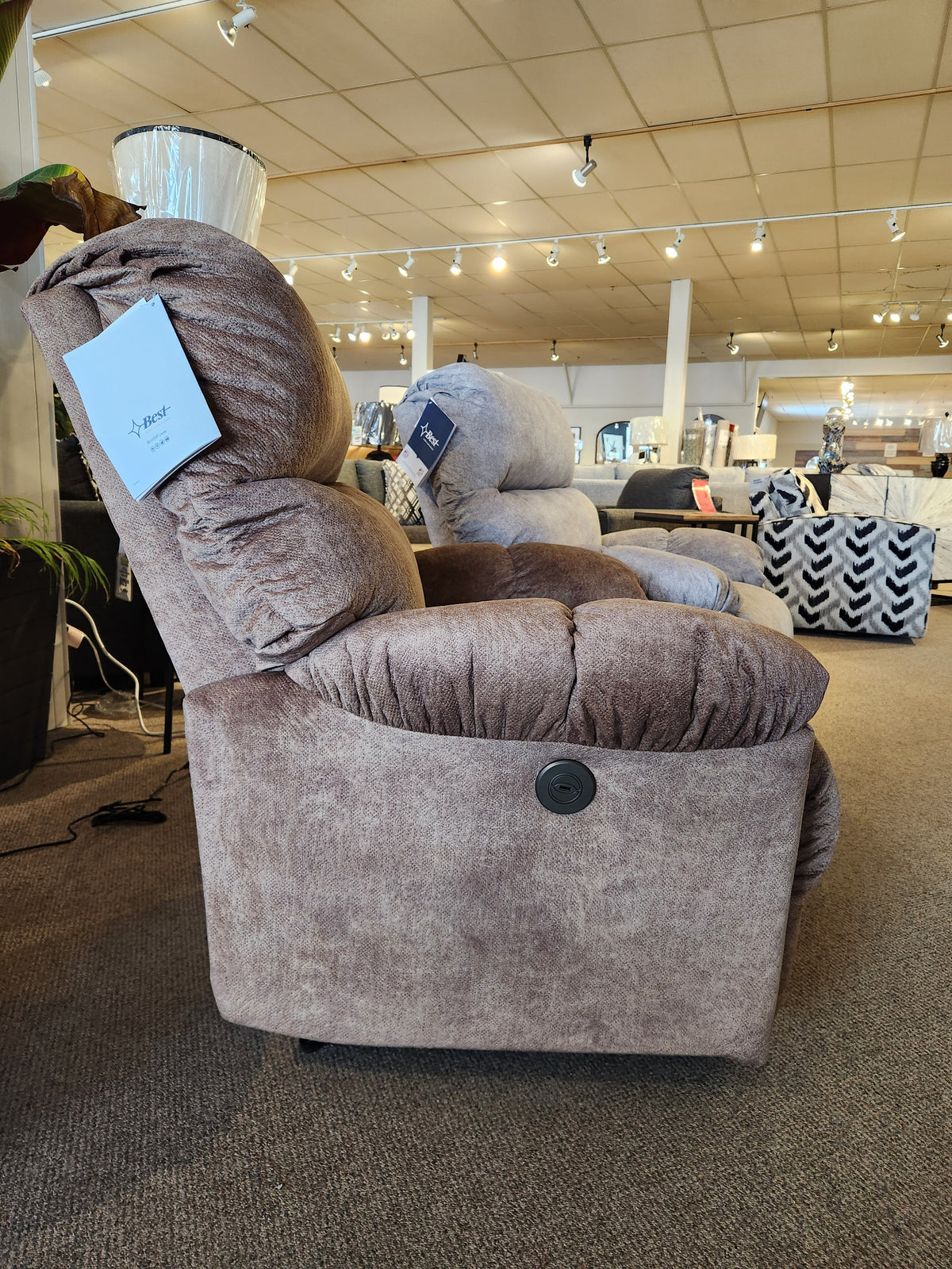 Side view of the Best 7MP84 Ellisport Power Space Saver Recliner with control button, shown in a furniture showroom.