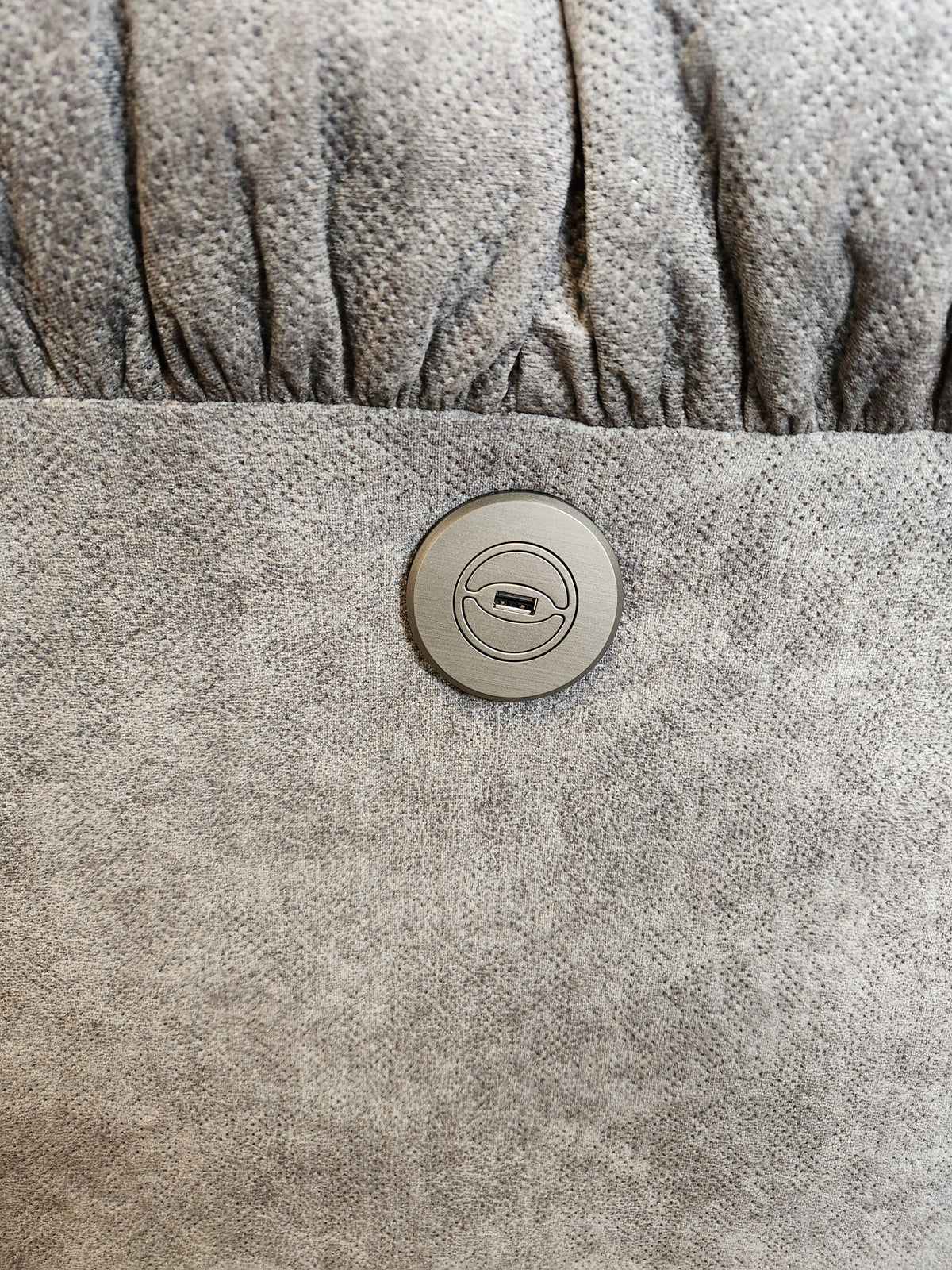 Close-up of a round metal lock on gray fabric—part of the Best 7MP84 Ellisport Power Space Saver Recliner.