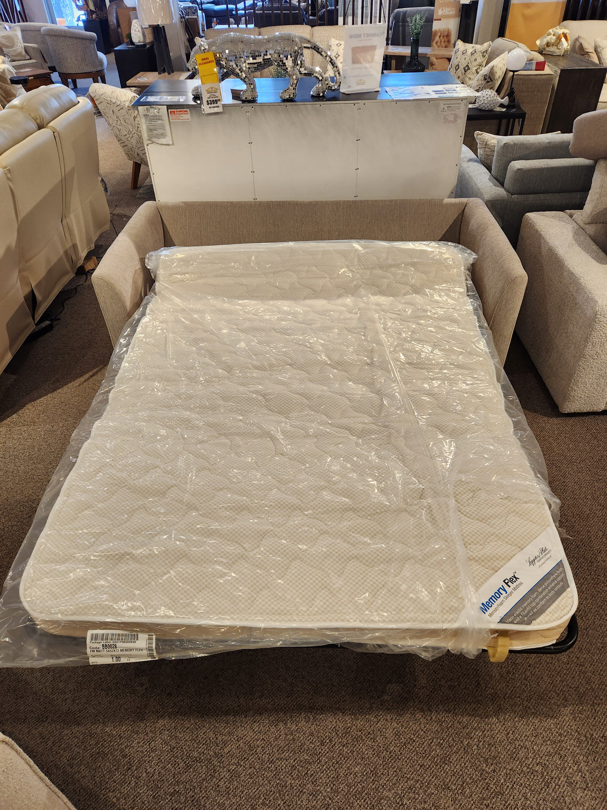 The Bayment Double Sofa Bed by Best is shown extended open with a plastic-covered memory foam mattress in a showroom.