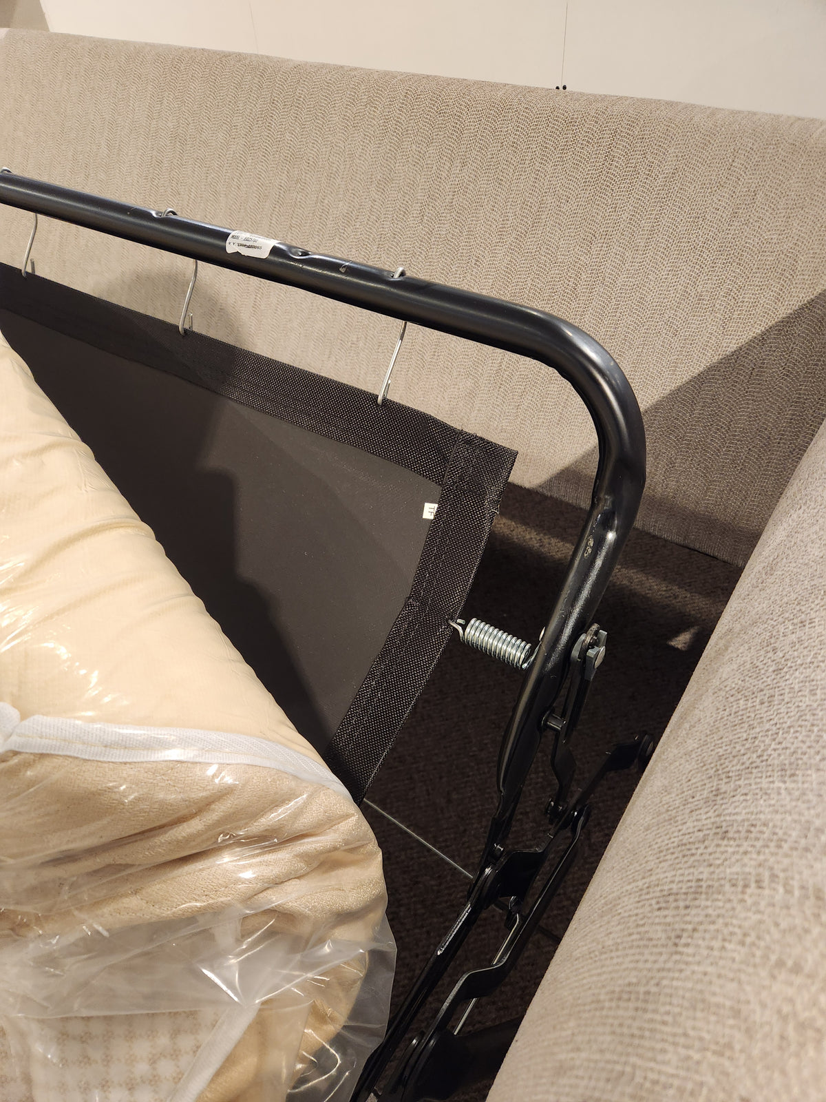 Close-up of the Best Bayment Double Sofa Bed’s metal frame and memory foam mattress, partially unfolded by beige couches.