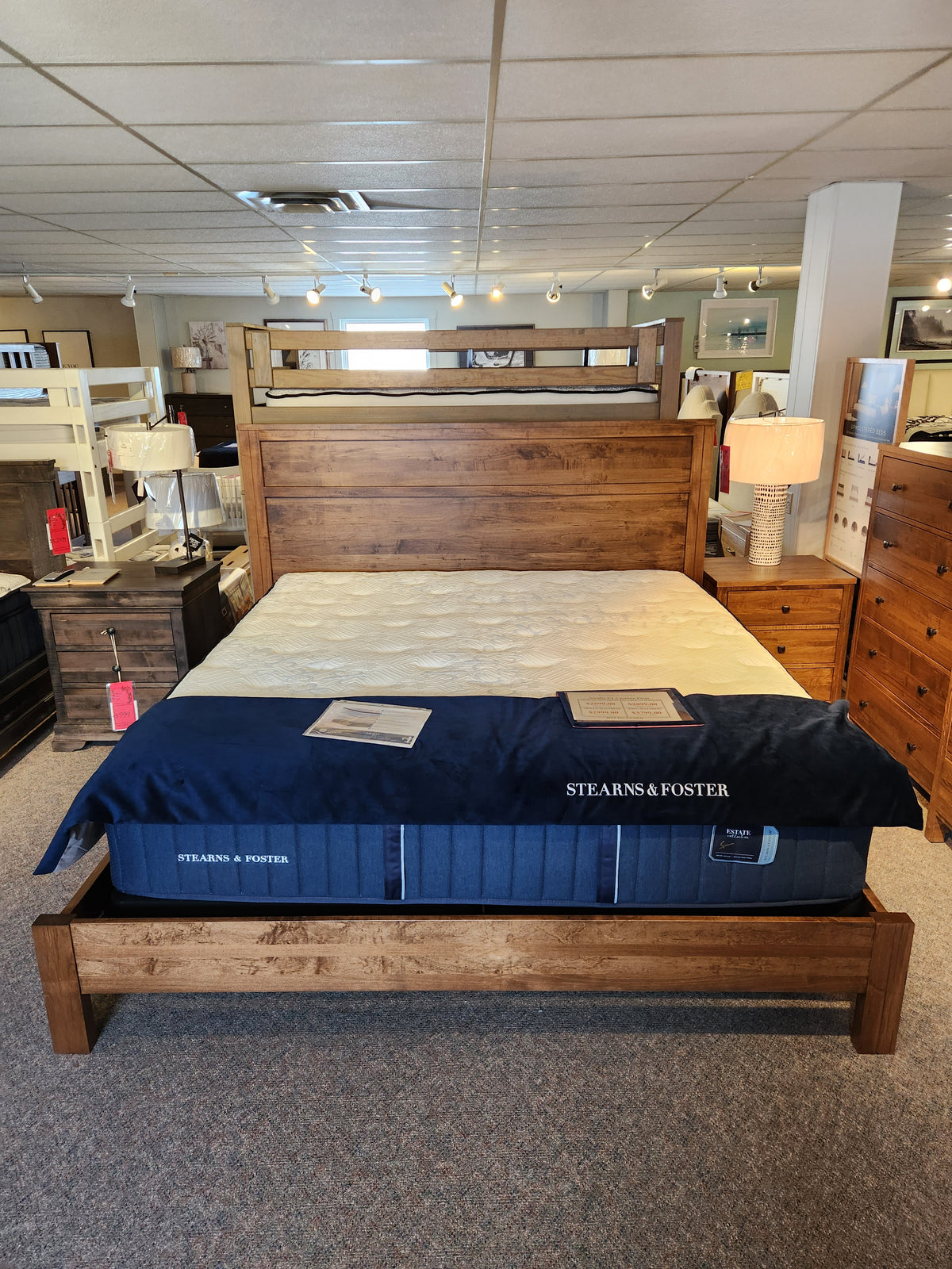 The Vokes 247 Vokes Saugeen King Bed Frame, with mattress, is displayed in a Canadian furniture showroom.