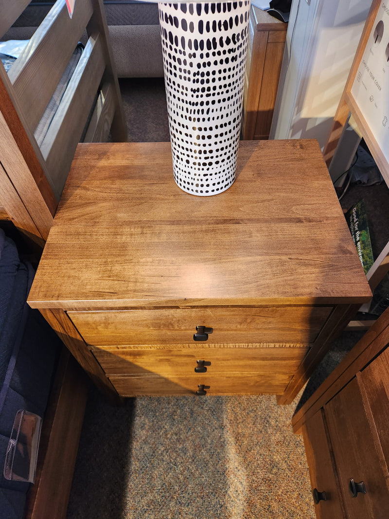 The Vokes 247 Saugeen 3 Drawer Nightstand is topped with a tall white vase featuring a black dotted pattern.