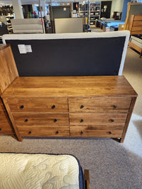 The Vokes 247 Saugeen 6 Drawer Dresser stands on a carpeted showroom floor near mattresses and bed frames.