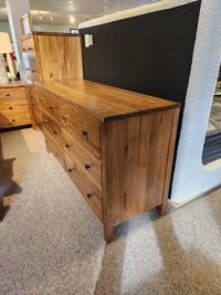 The Vokes 247 Saugeen 6 Drawer Dresser with black handles is displayed in a furniture showroom.