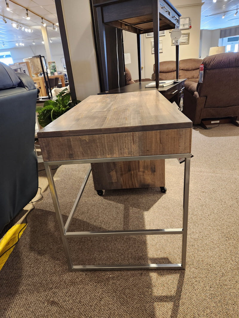 A Handstone EL2448 Electra Writing Desk in driftwood heritage maple with metal legs highlights the showroom.