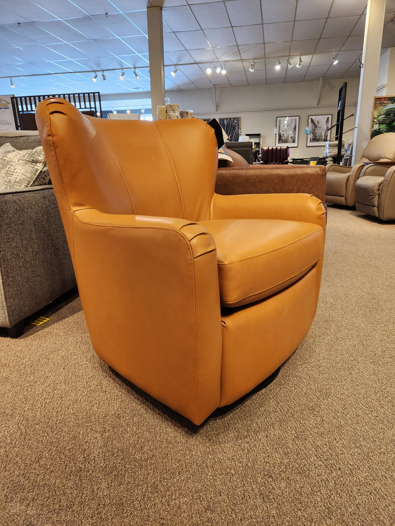 The Palliser 77115 Scarlett Swivel Chair in tan leather features a reversible seat cushion on the showroom floor.