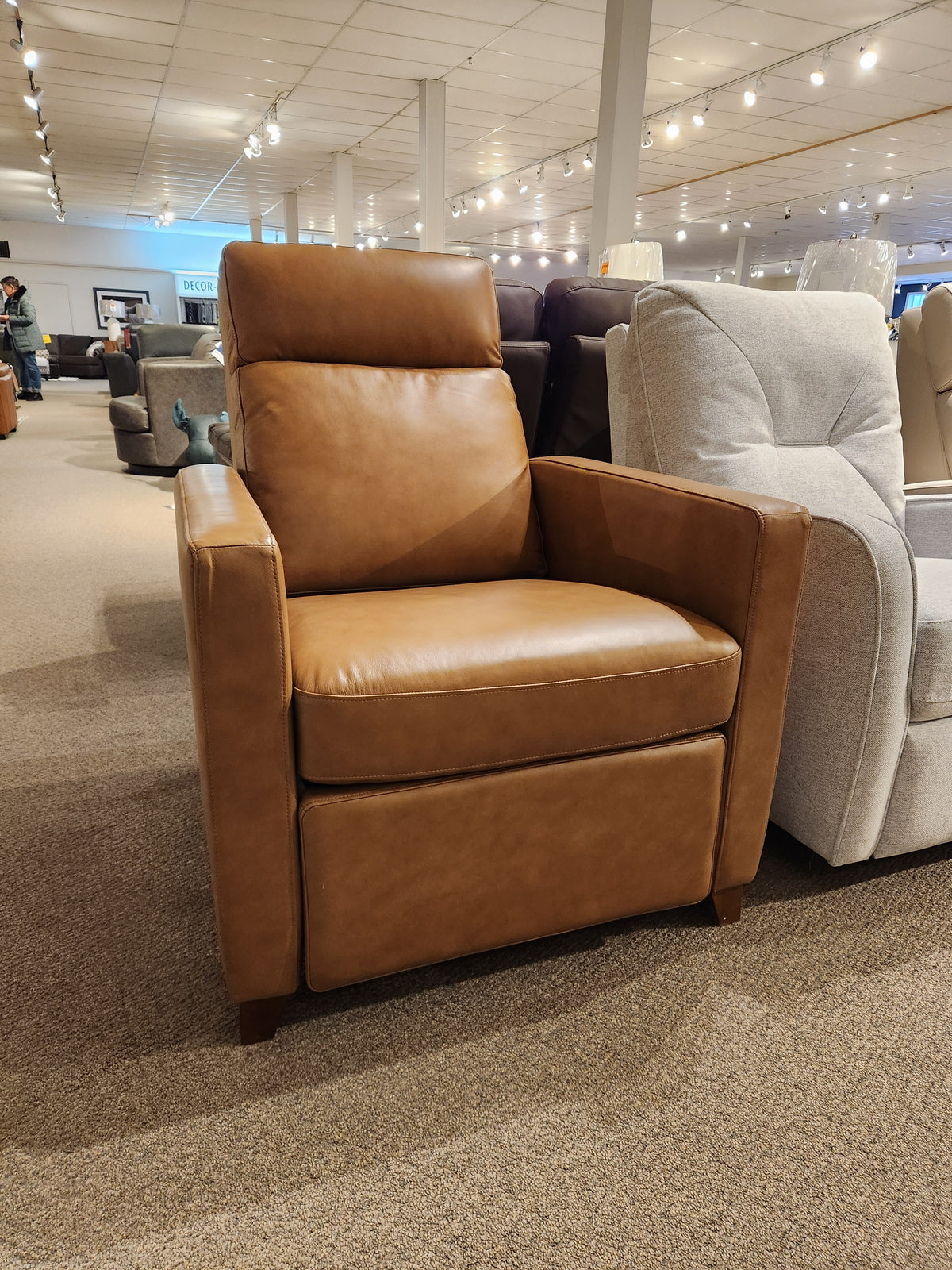 The Palliser 77171 Soren Push-Back Reclining Chair in tan leather with tapered wooden legs is on showroom display.