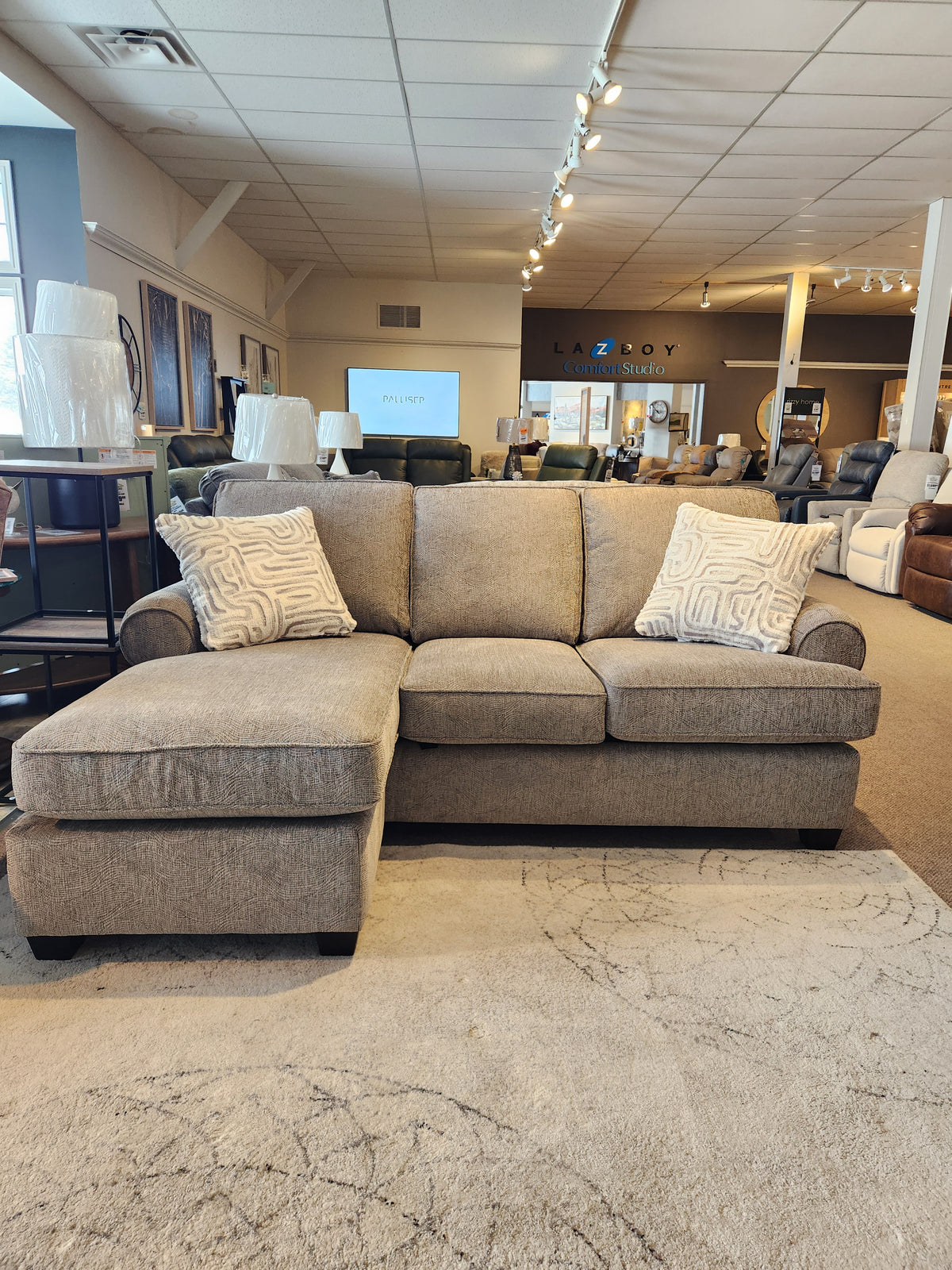 The Decor-rest 2285 Sofa with Chaise, gray with sinuous springs and two patterned cushions, is shown in the showroom.