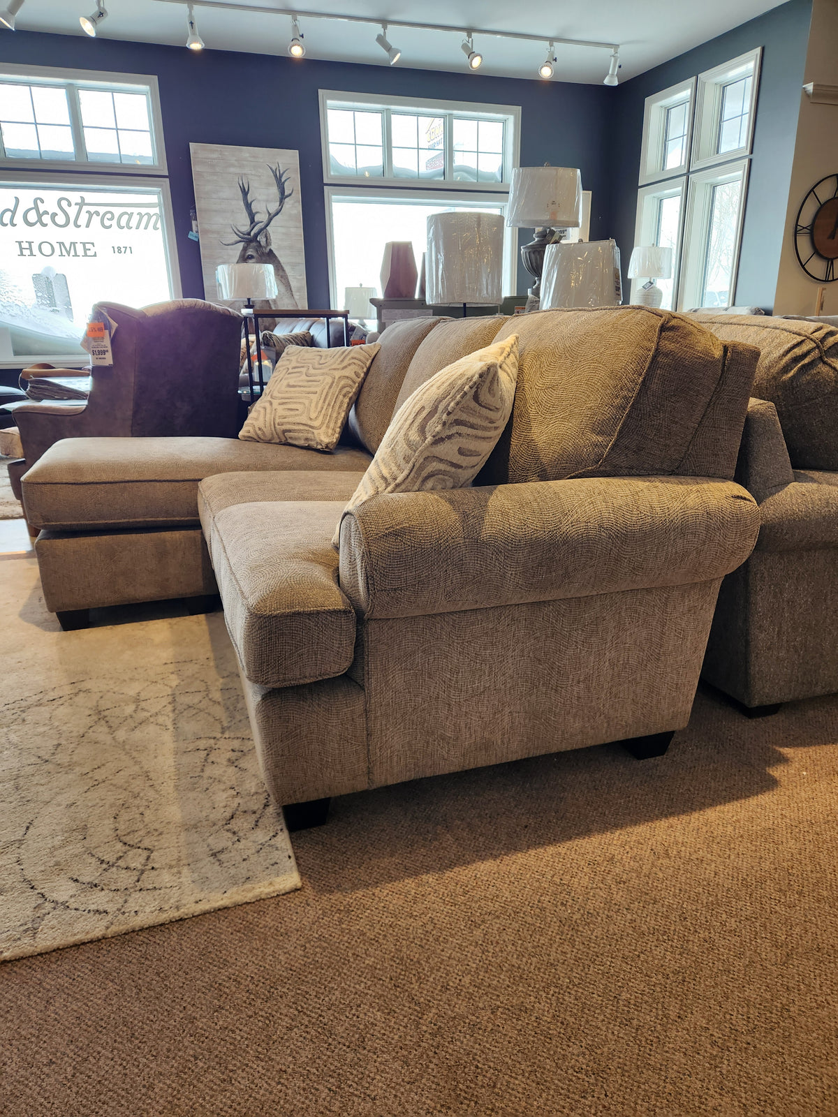The Decor-rest 2285 Sofa with Chaise in beige, featuring patterned pillows and spring construction, is in the showroom.