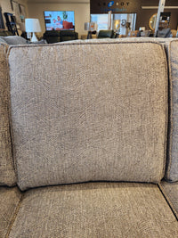 Close-up of a textured beige cushion on the Decor-rest 2285 Sofa with Chaise, with lamps and chairs in the background.