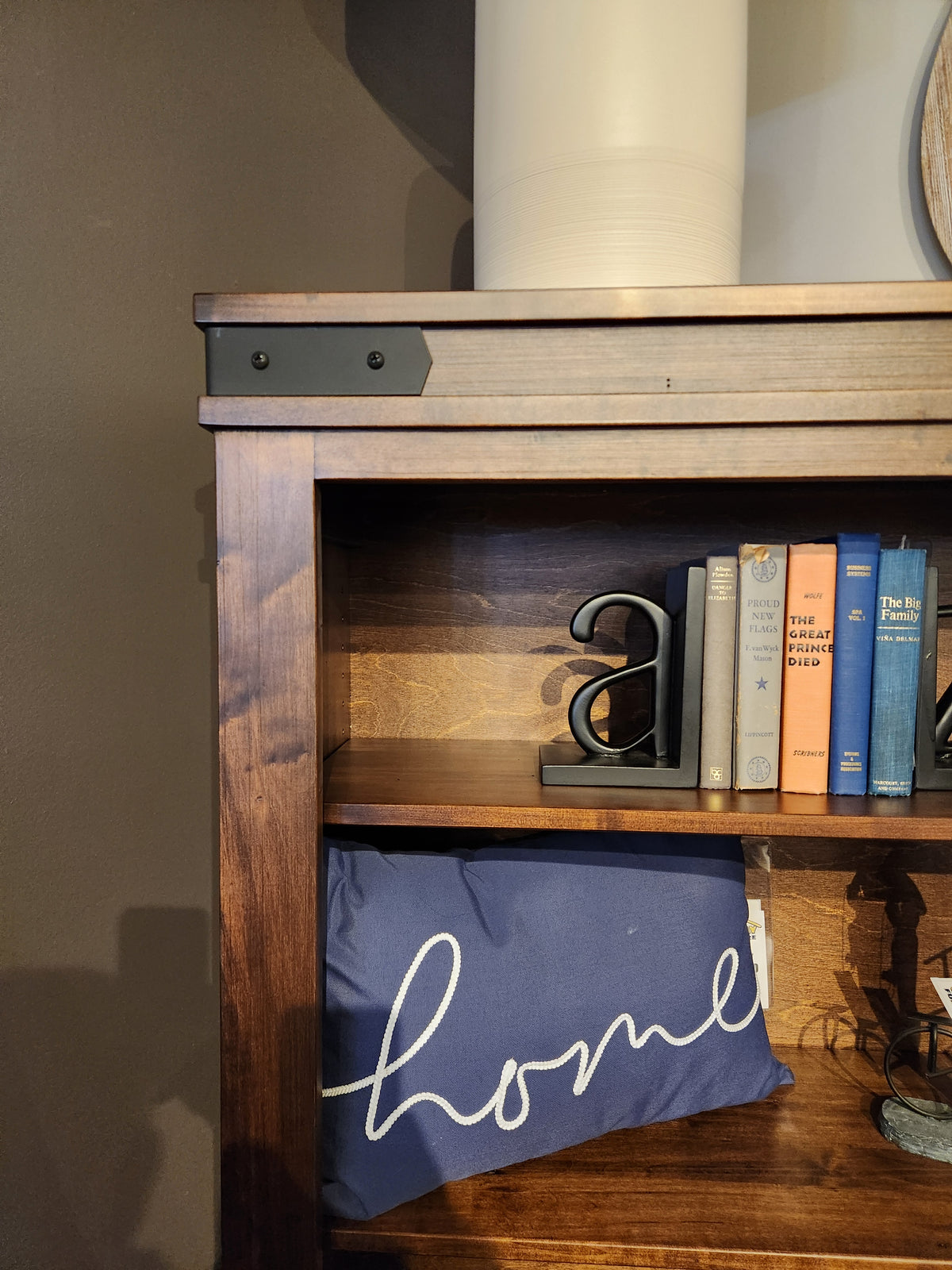 Handstone CH75 Chattanooga 54" bookcase in maple mocha finish with books, metal "a," white vase, and "home" pillow.