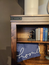 Handstone CH75 Chattanooga 54" bookcase in maple mocha finish with books, metal "a," white vase, and "home" pillow.