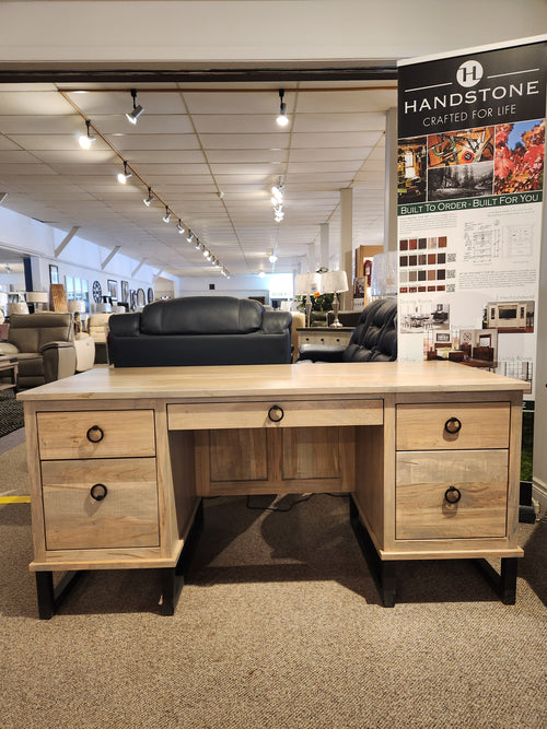 The Handstone CU2864-Cumberland Executive Desk with four drawers is showcased in a furniture showroom.