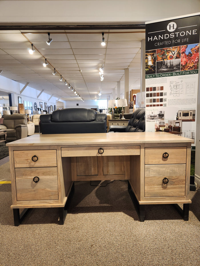 The Handstone CU2864-Cumberland Executive Desk with four drawers is showcased in a furniture showroom.