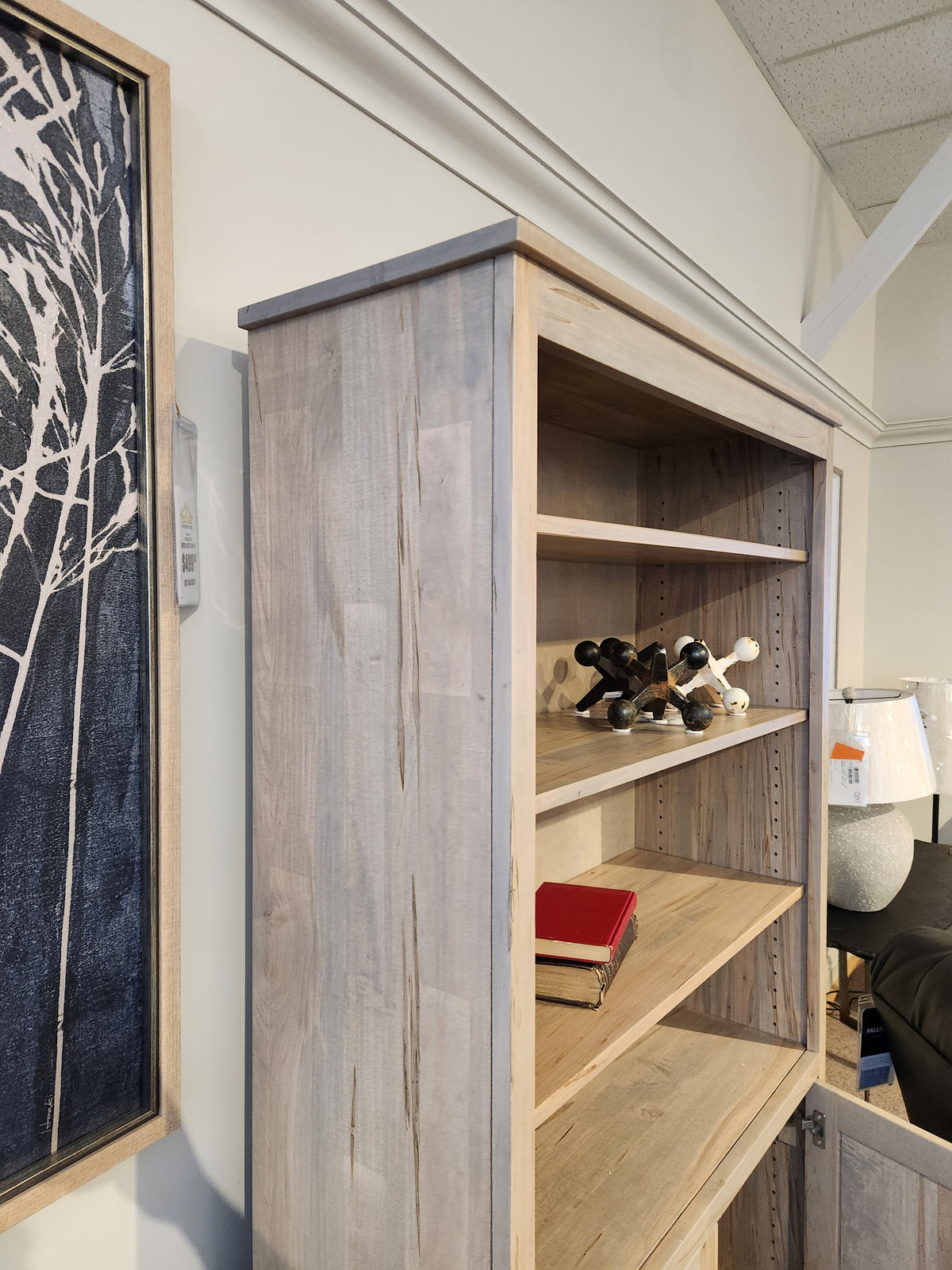 The Handstone CU80D-Cumberland Bookcase provides vertical storage for books and decor beside art on a white wall.