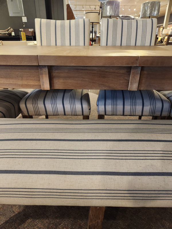 Jofran 6-piece Eastern Tides Dining Table set with striped chairs displayed in a furniture showroom.